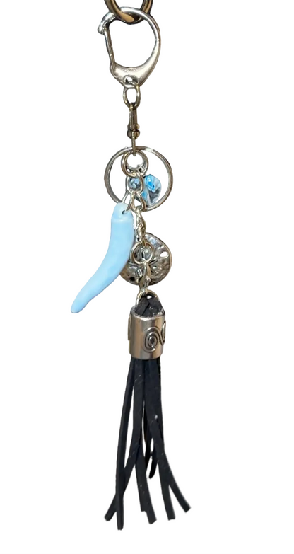 Handbag with decorative charm featuring a black tassle, silver sand dollar, porcelain pepper charm