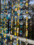 Colorful beaded strands with a blurred natural background