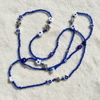 Blue wasitbeads with white flowers and silver metal turtles on a light background