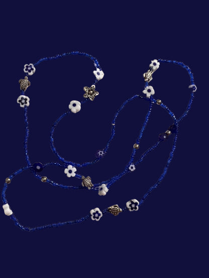 Blue wasitbeads with white flowers and silver metal turtles on a light background