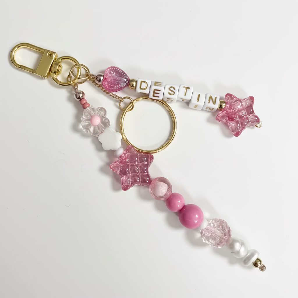 Beaded keychain with pink and gold accents on a gray background