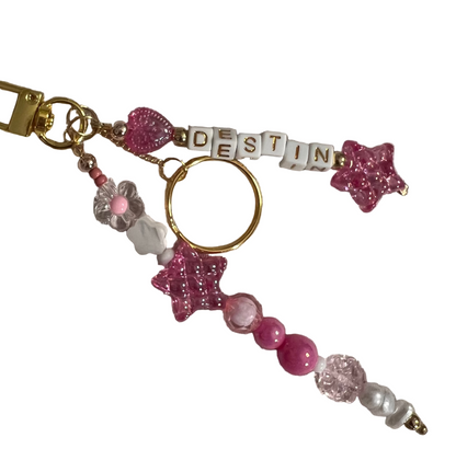 Beaded keychain with pink and gold accents on a gray background