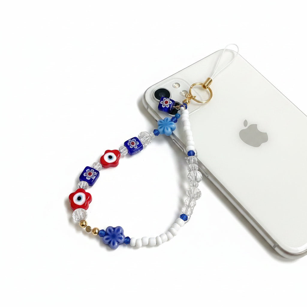 Beaded wristlet with blue, red, and white evil eye designs on a beige background
