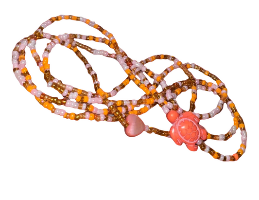 Beaded waistbeads with pink heart and flower pendant on a coral background