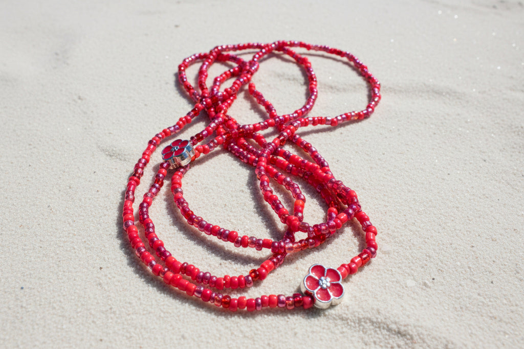 Red waistbeads on sandy background 