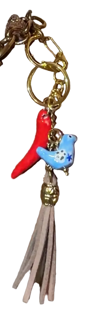 Handbag with decorative charm featuring a beige tassle, porcelain blue hen, porcelain pepper charm