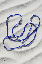 Blue waistbeadswith white flowers and silver turtles on a light background