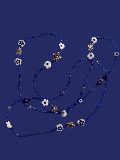 Blue waistbeadswith white flowers and silver turtles on a light background