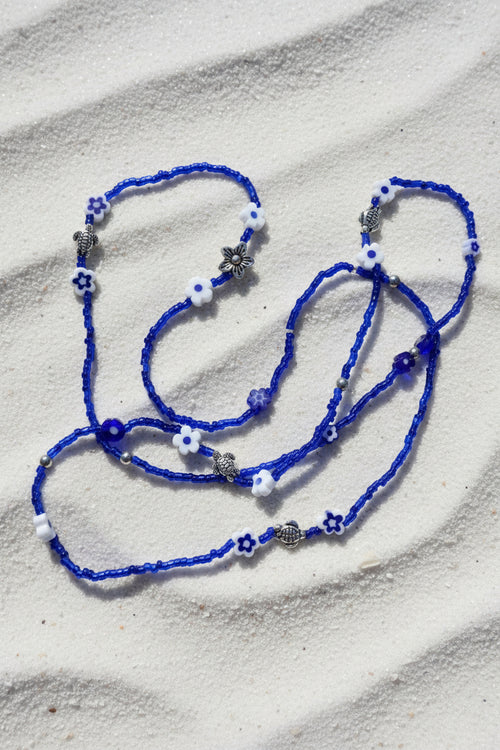 Blue waistbeadswith white flowers and silver turtles on a light background
