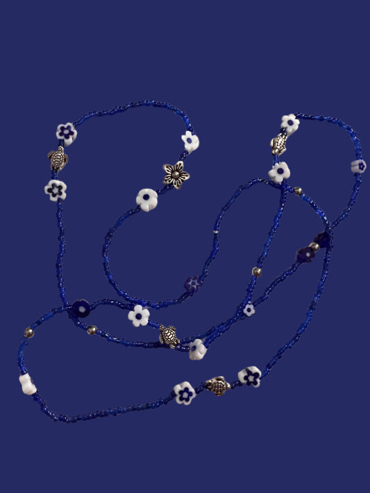 Blue waistbeadswith white flowers and silver turtles on a light background