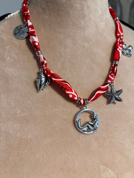Red and silver bandana necklace with starfish charms on a neck.