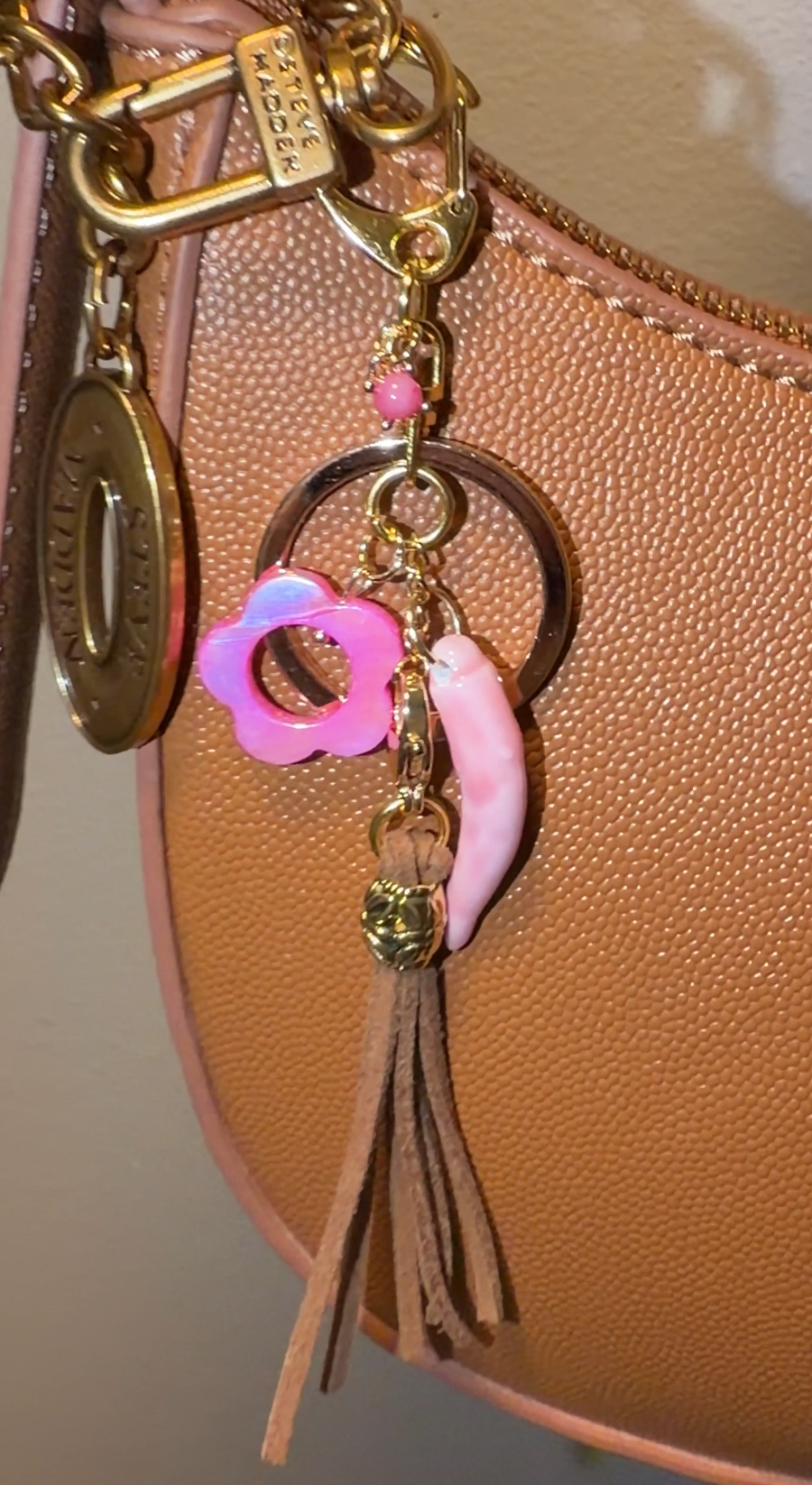 Handbag with decorative charm featuring a light bronze tassle, pink flower, pink porcelain pepper