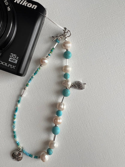 Pearl and turquoise beaded camera wristlet with charms on a Nikon camera 