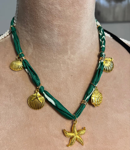 Green bandana necklace with gold starfish and shell charms on a neck.