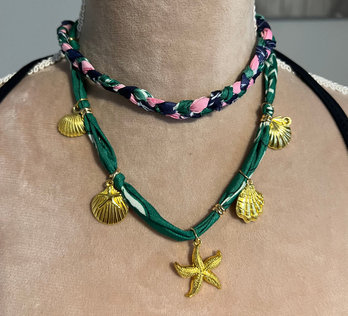 Green braided necklace with gold starfish and shell charms on a nec.