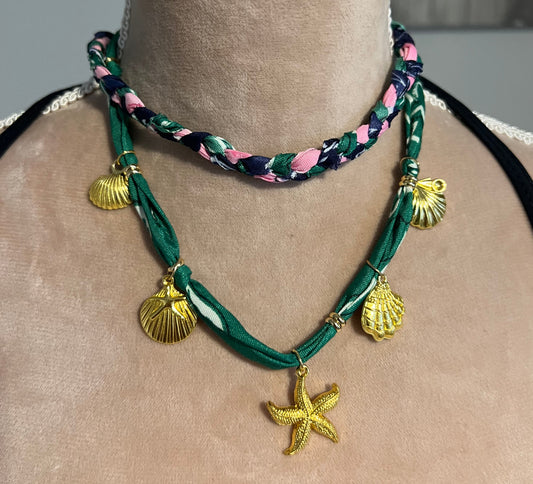 Green braided necklace with gold starfish and shell charms on a nec.