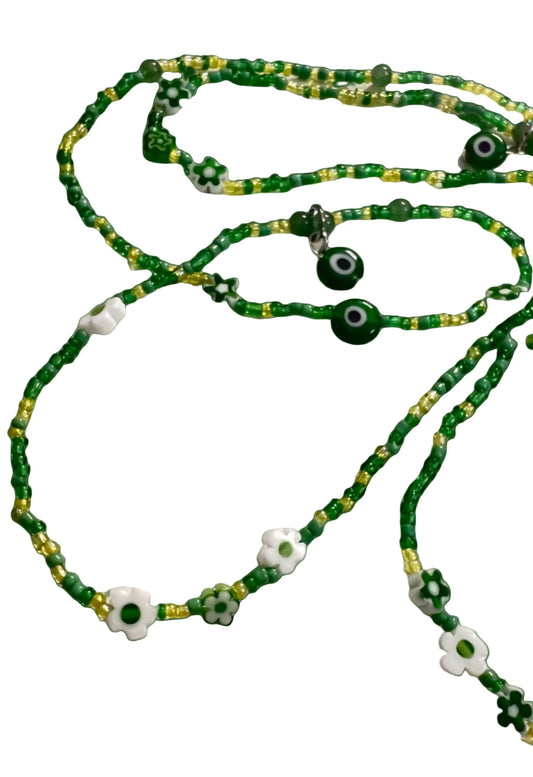 Green waistbeads with eye-shaped beads on a white background