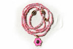 Pink beaded waistbeads with a flower pendant on a wooden surface