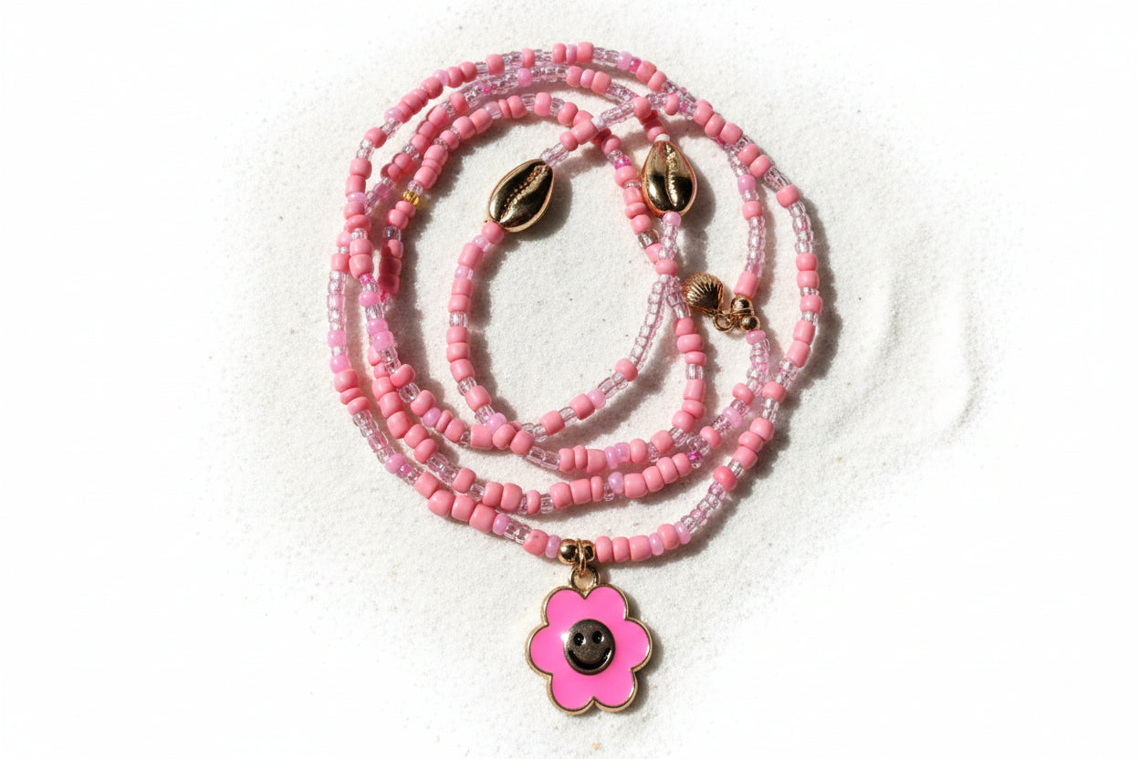 Pink beaded waistbeads with a flower pendant on a wooden surface