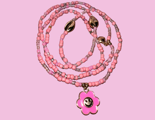 Pink beaded waistbeads with a flower pendant on a wooden surface