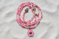 Pink beaded waistbeads with a flower pendant on a wooden surface