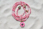 Pink beaded waistbeads with a flower pendant on a wooden surface