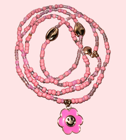 Pink beaded waistbeads with a flower pendant on a wooden surface