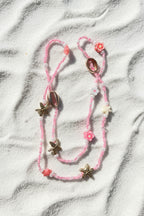 Pink with starfish and shell charms on a white sand background