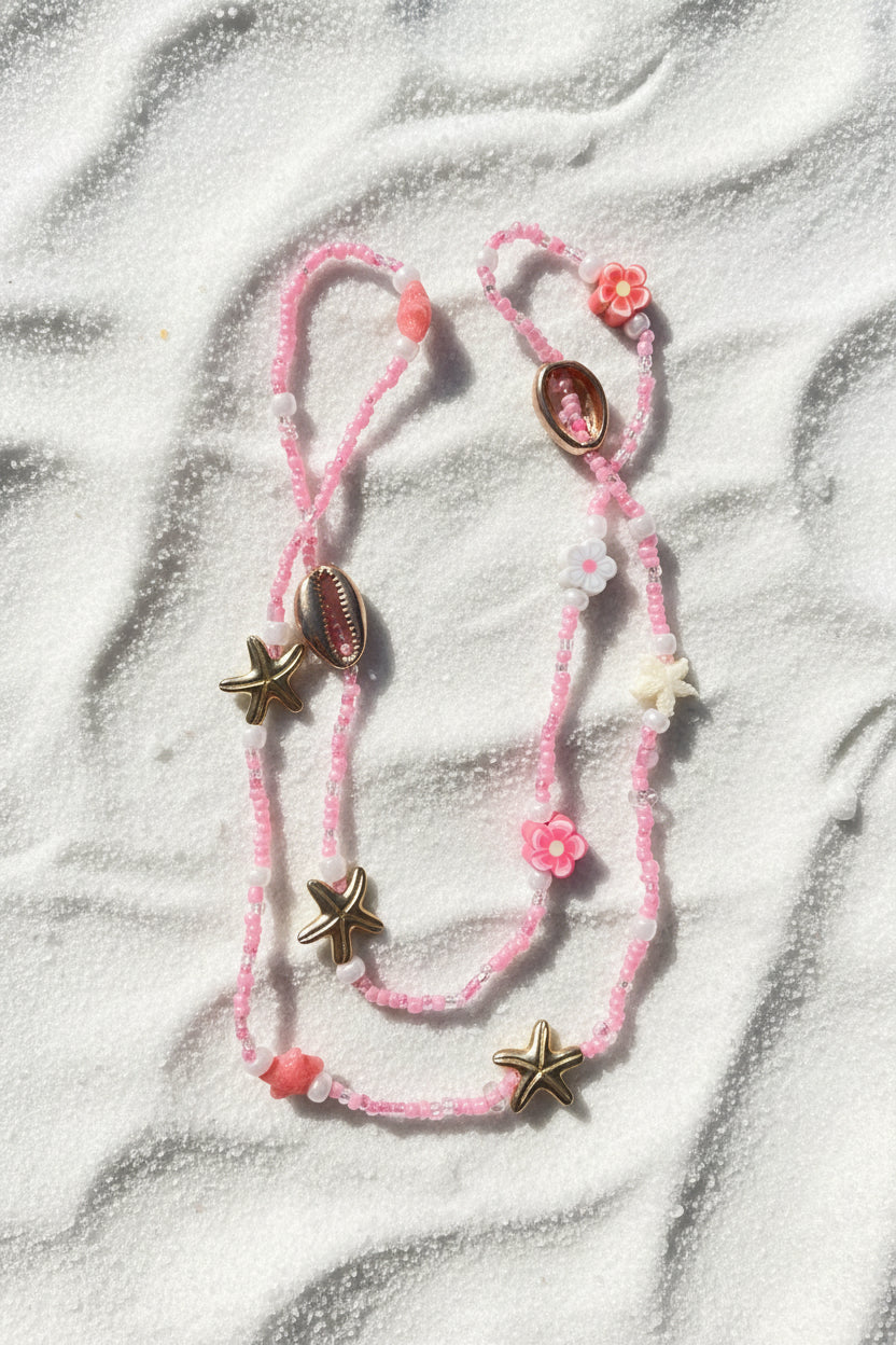 Pink with starfish and shell charms on a white sand background