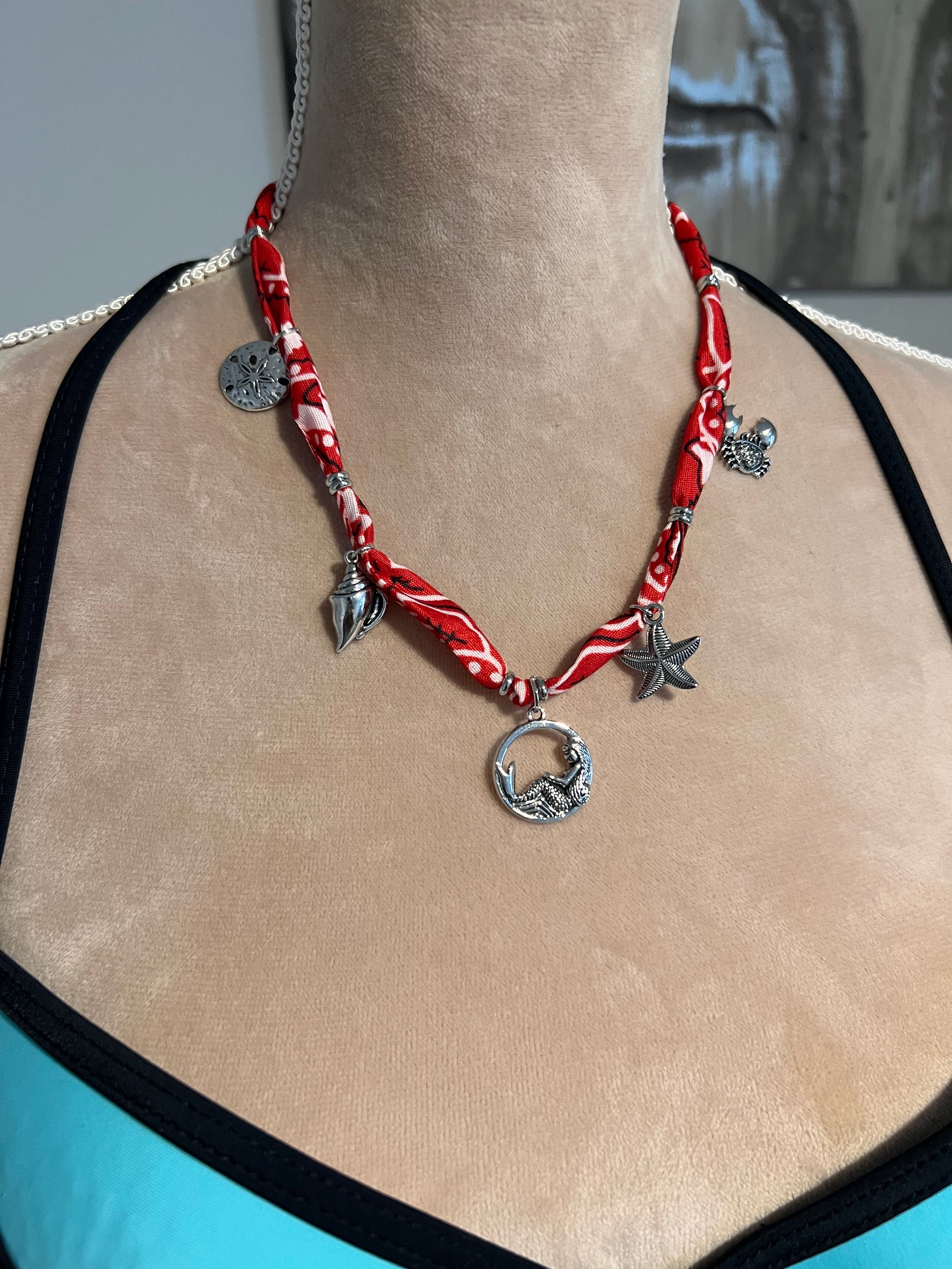 Red and silver bandana necklace with starfish charms on a neck.