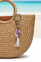 Handbag with decorative charm featuring a grey tassle, purple seaturtle, tahitian pearl, porcelain pepper charm
