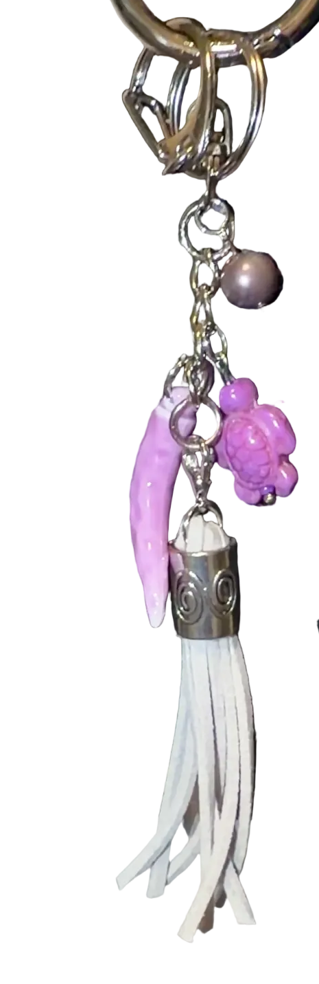 Handbag with decorative charm featuring a grey tassle, purple seaturtle, tahitian pearl, porcelain pepper charm