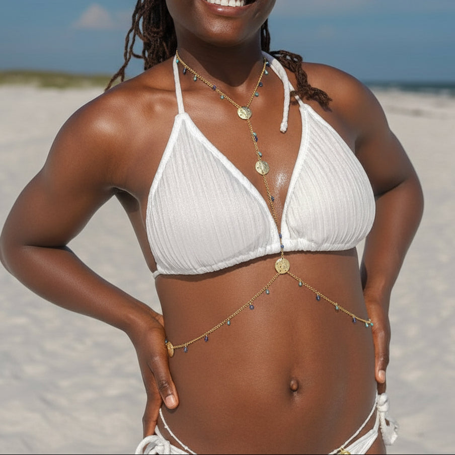 Woman in a white bikini standing on a sandy beach with a blue sky.