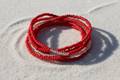 Red waistbeads on beachy sand