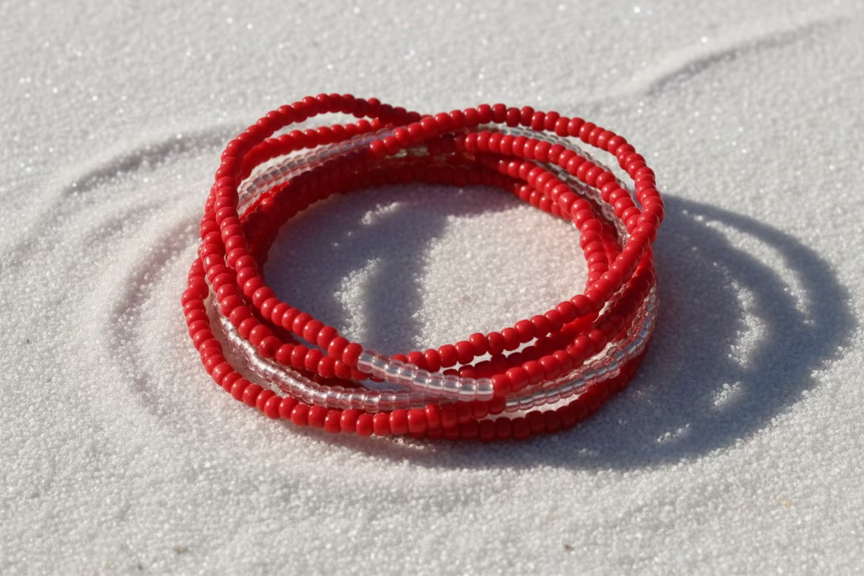 Red waistbeads on beachy sand