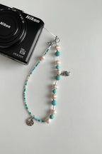 Pearl and turquoise beaded camera wristlet with charms on a Nikon camera 