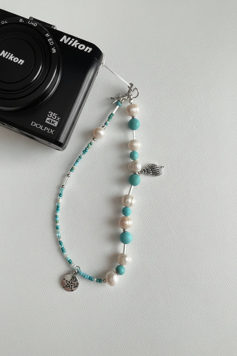 Pearl and turquoise beaded camera wristlet with charms on a Nikon camera 